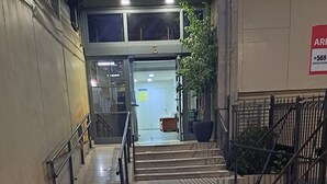 En korridor med ett metallräcke, en dörr med nummer 3 och en skylt med kontaktinformation på väggen.