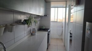Ett modernt kök med vita skåp, en bänkskiva, en växt och ett fönster.