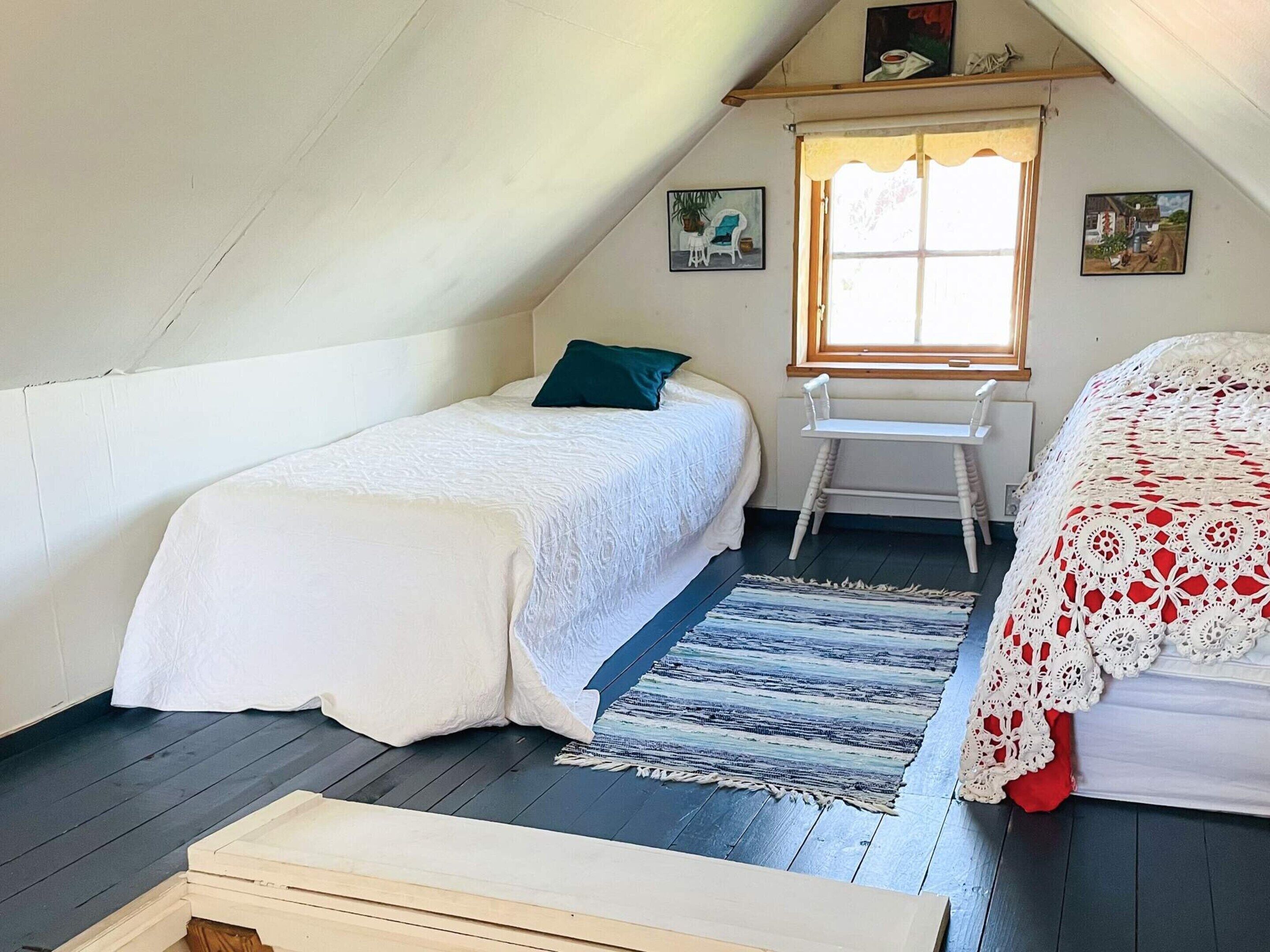 Een kleine, gezellige kamer met een bed, een stoel, een tafel en een raam.