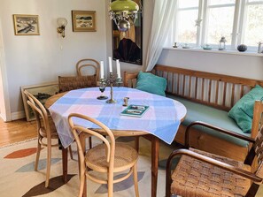 A cozy dining area with a round table, chairs, a bench, and a window with curtains. - 6 Person Holiday Home in Lovestad (Lövestad)