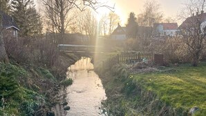 Een rustige rivier met een brug, omringd door bomen en huizen.