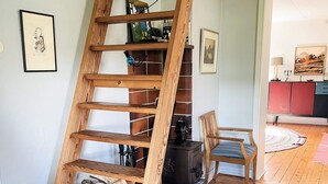 Een houten trap met een open haard, een stoel en een rode kast in een kamer met houten vloeren.