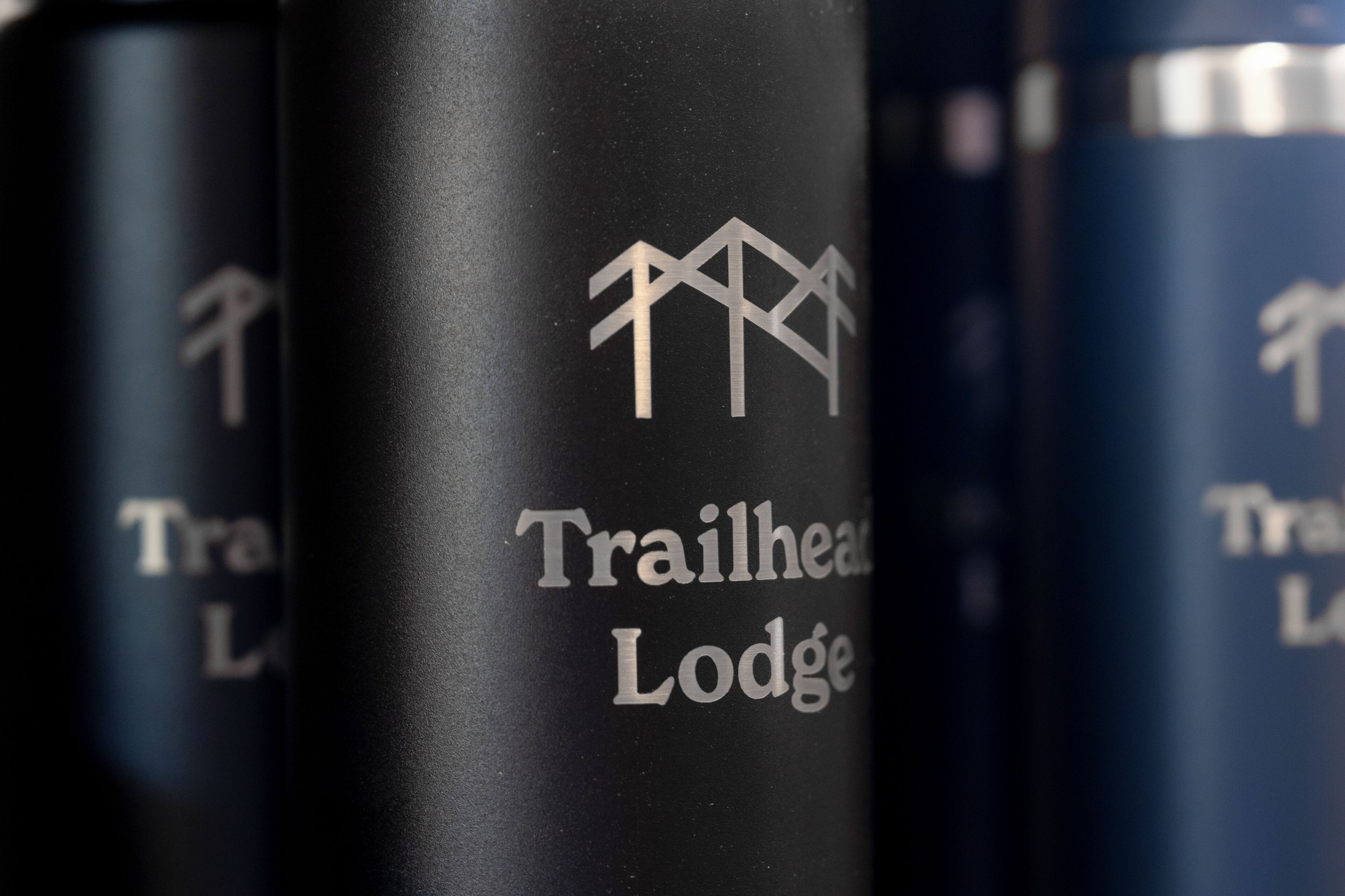 Gros plan d’un récipient cylindrique sur lequel on peut lire le texte « Trailhead Lodge » et qui est orné d’un symbole de montagne.