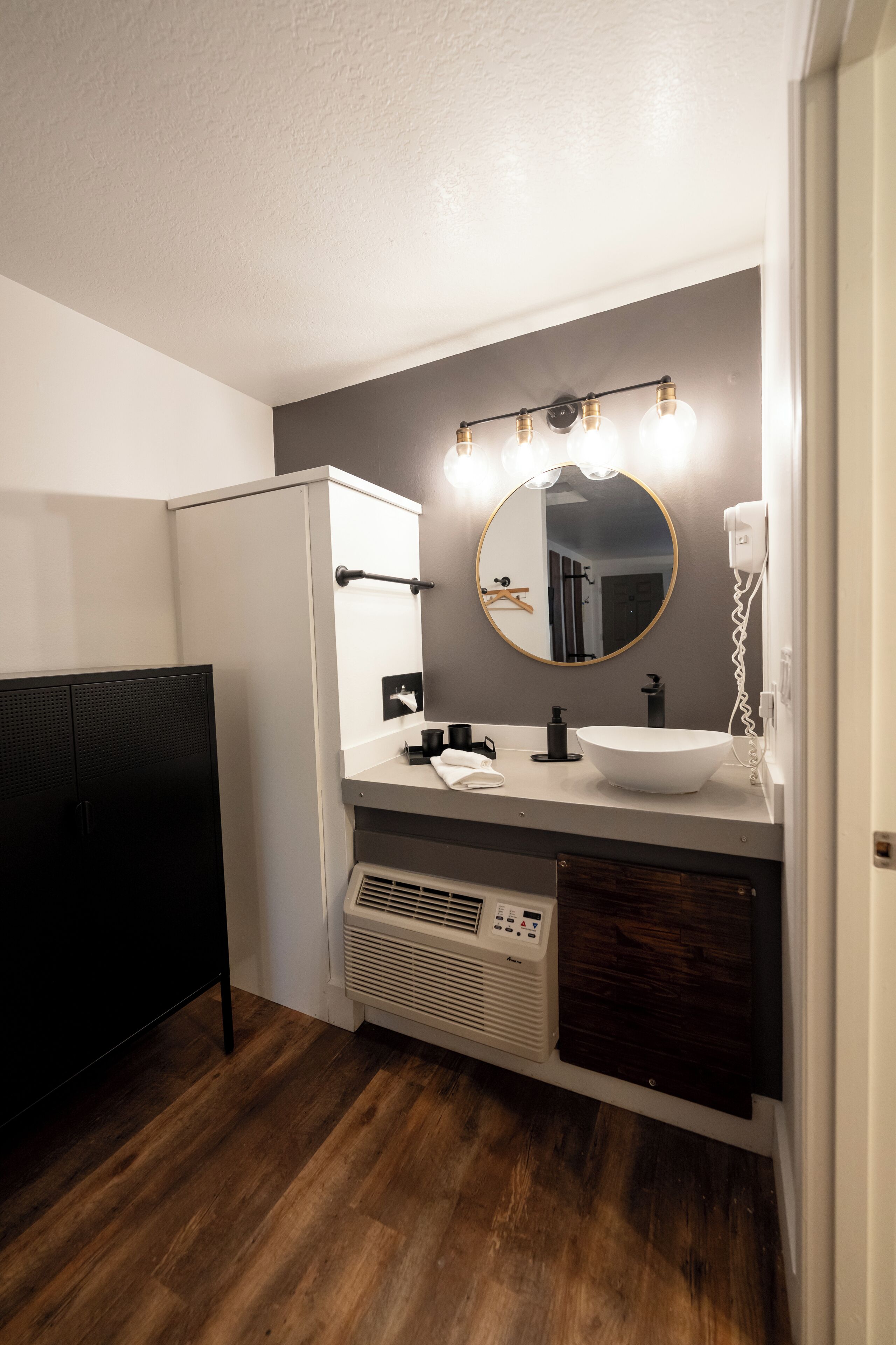 A bathroom with a white sink, mirror, and light fixture.