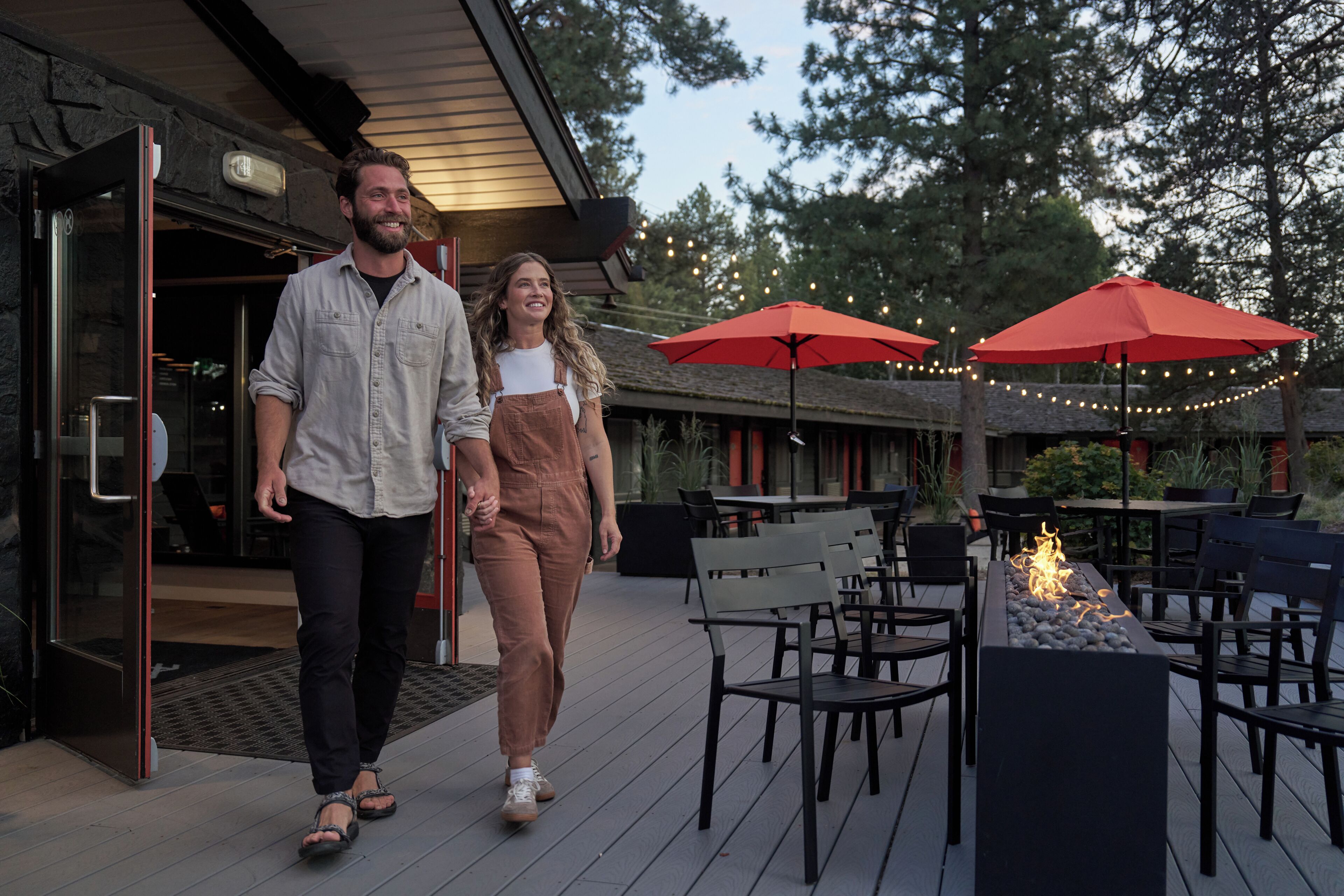 A couple walking on a wooden deck with outdoor seating and a fire feature.