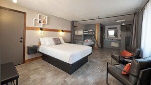 A hotel room with a bed, a desk, a chair, a wardrobe, a mirror, and a kitchenette. - Trailhead Lodge (Bend)