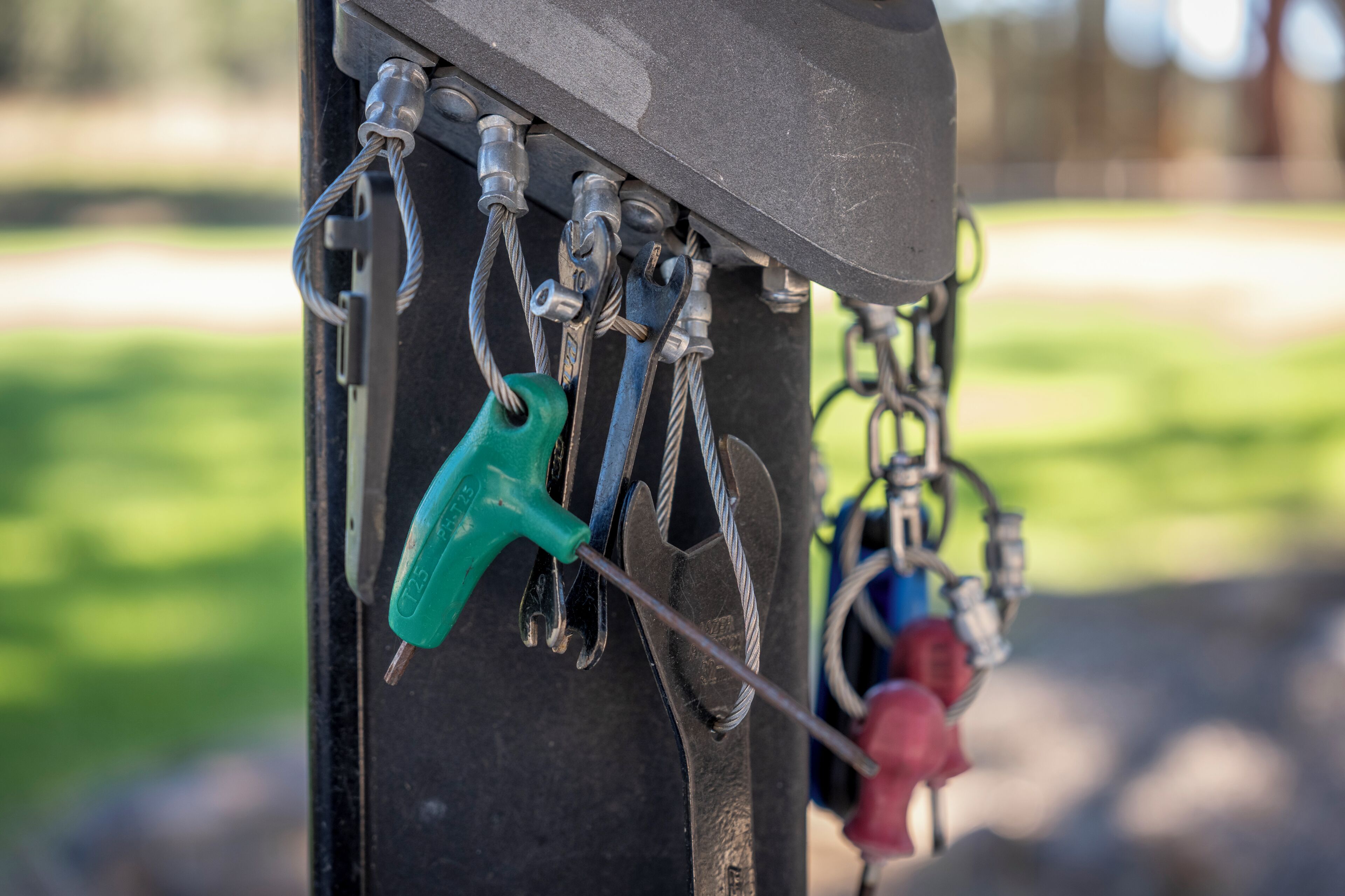 A close-up of a metal structure with various tools and a green tool hanging from it.