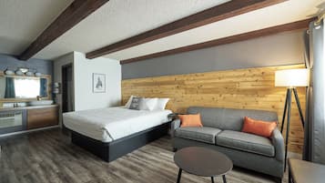 A bedroom with a bed, a sofa, a small table, a lamp, and a wooden wall.