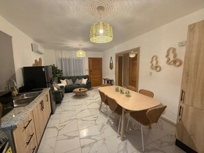 A modern kitchen with a dining area, a sofa set, and a TV. - Punta Cana Stay w/ Pool, Near Beach & Downtown + 360 Experience (Punta Cana)