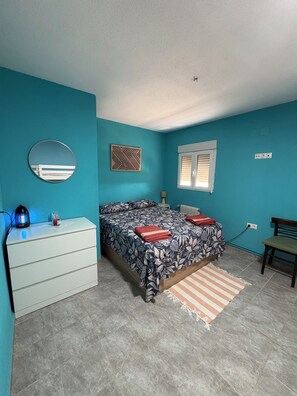 A bedroom with a bed, a dresser, a mirror, a window, and a radiator.