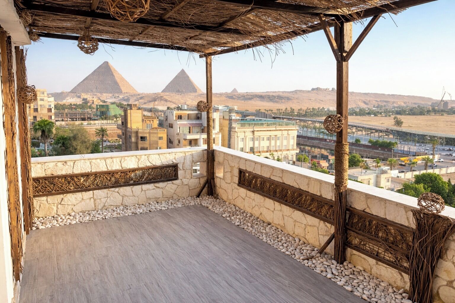 A balcony with a view of the pyramids, stone walls, and a thatched roof.