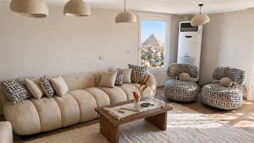 Ein Wohnzimmer mit einer Couch, zwei gemusterten Sesseln, einem Couchtisch und hängenden Pendelleuchten.