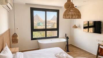 Ein modernes Schlafzimmer mit großem Fenster, Badewanne und Blick auf Pyramiden.