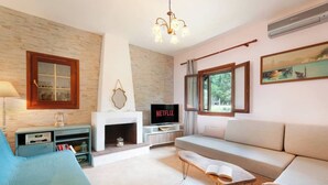 Una sala de estar con chimenea, un sofá, un televisor y una estantería.