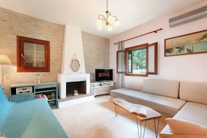 A living room with a fireplace, a sofa, a TV, and a bookshelf. - Beachfront Private house in Vourvourou, Chalkidiki with amazing view (Vourvourou)