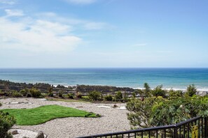 A coastal landscape with a pebble beach, a grassy area, and a view of the ocean.