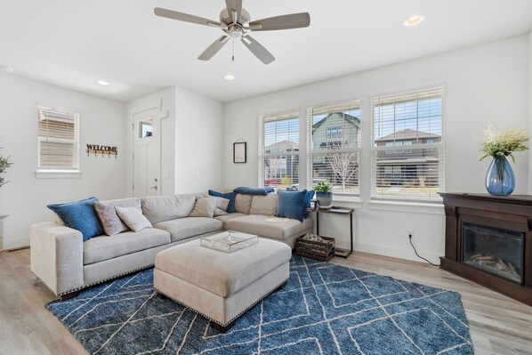 A living room with a sectional sofa, ottoman, and a blue rug. - Stillwater Retreat - Beautiful 3 bedroom townhouse in belgrade (Belgrade)