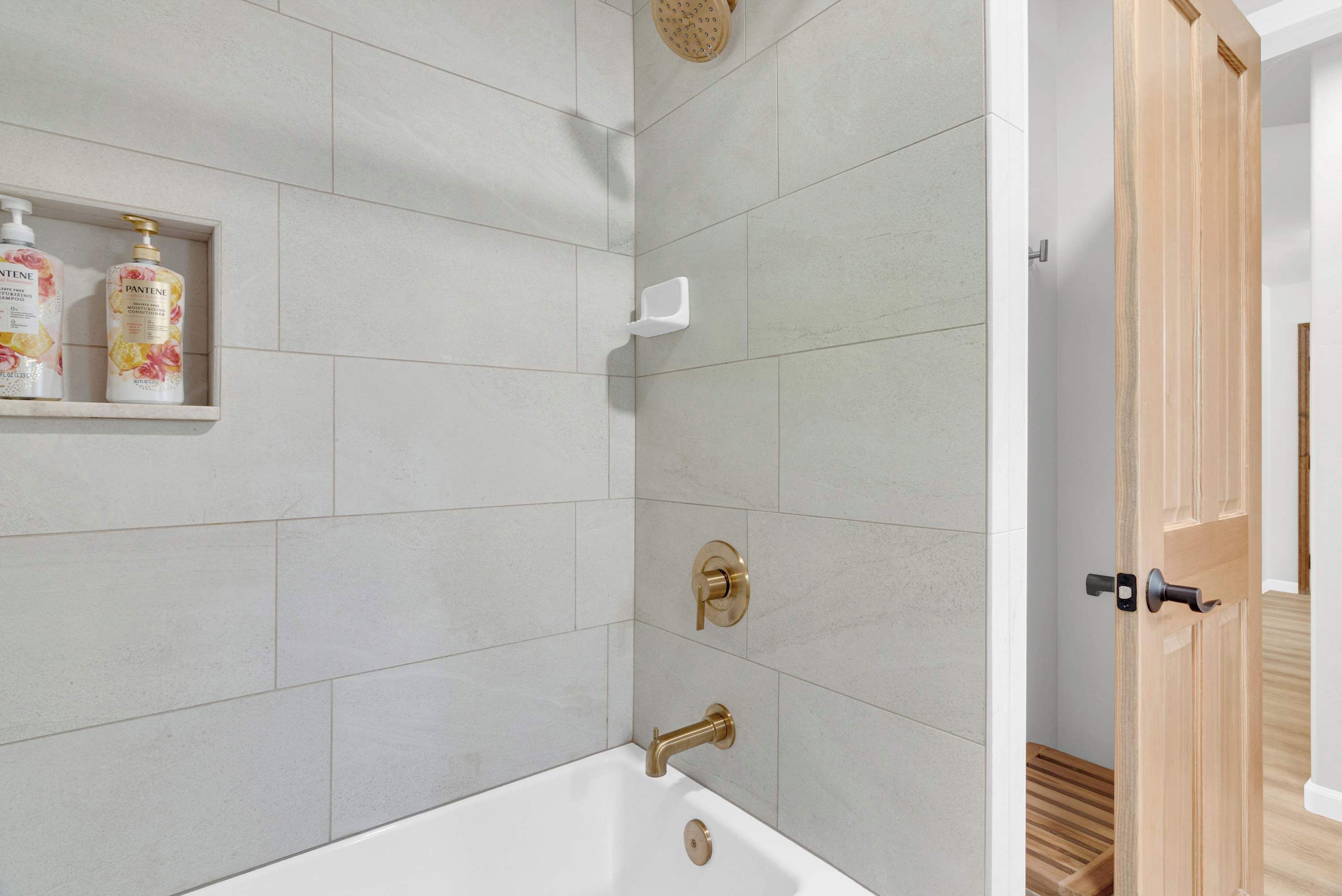 Une salle de bain avec une baignoire, une douche et une étagère où sont rangées les produits de toilette.