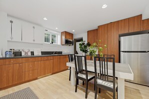 Eine moderne Küche mit Holzausstattung, einem Edelstahlkühlschrank und einem Esstisch mit Stühlen.