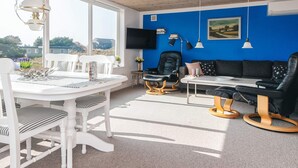 Una habitación con una mesa de comedor, sillas, un sofá y un televisor.