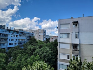 A multi-story residential building with balconies, surrounded by dense greenery.