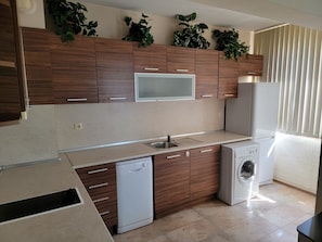 A modern kitchen with wooden cabinets, a built-in microwave, a dishwasher, and a washing machine.