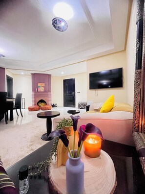 Ein modernes Wohnzimmer mit Sofa, Wand-Fernseher, Kamin und Essbereich mit Tisch und Stühlen.