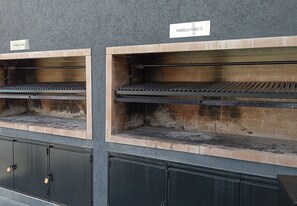 Twee buitenovens van baksteen met de tekst 'PARRILLA NRO 1' en 'PARRILLA NRO 2', met metalen kastjes eronder.