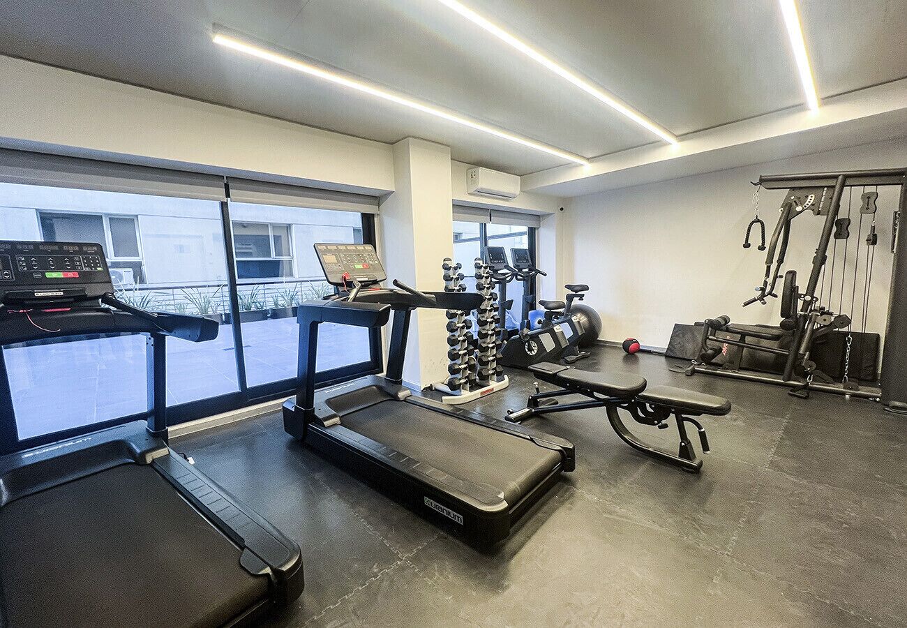 Ett gym med löpband, en bänk, styrketräningsmaskiner och en roddmaskin.