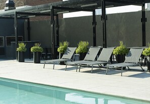 A poolside area with lounge chairs and potted plants.