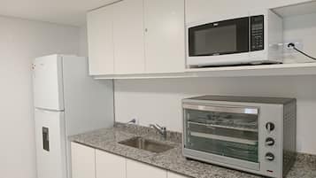 A kitchen with a white refrigerator, a microwave, and a toaster oven.