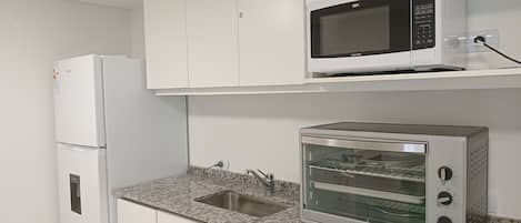 Una cocina con un refrigerador blanco, un microondas y un horno tostador.