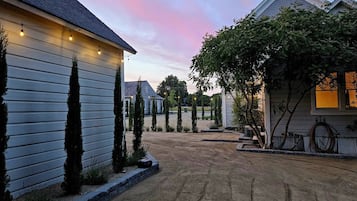 A residential driveway with a gravel surface, bordered by a low curb, and houses on either side.