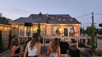 An outdoor patio area with a stage for live music, surrounded by guests.