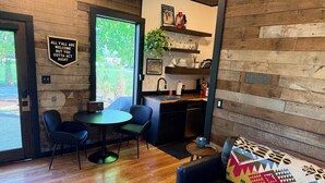 A cozy interior with a dining area, a sofa with a colorful throw, and a kitchen area.