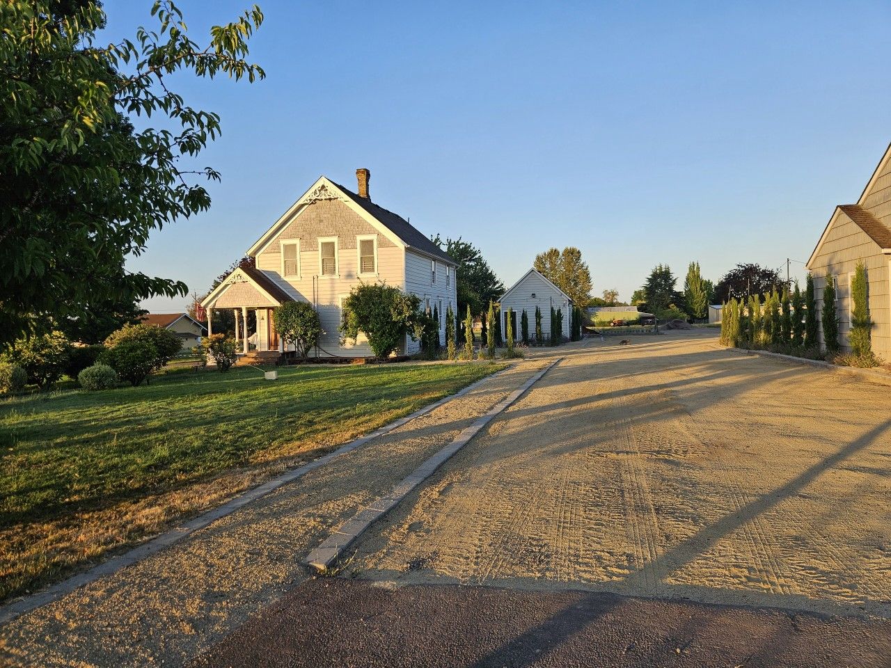 Eine Wohnstraße mit Häusern, blauem Himmel und einem Schotterweg.
