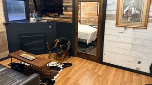 A room with a fireplace, a television, a bed, and a framed picture on the wall.
