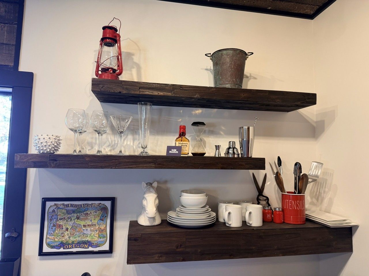 A kitchen with wooden shelves holding glassware, a lantern, and kitchen utensils.
