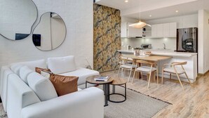 Een moderne woonkamer met een witte bank, een salontafel, en een eethoek met houten stoelen en een kleine tafel.