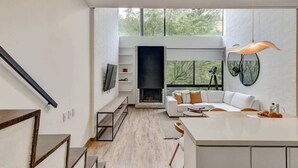 Een modern interieur met een trap, een open haard, een witte bank en een eethoek.