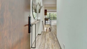 Een gang met een houten vloer, een spiegel en een trap naar een balkon met uitzicht.