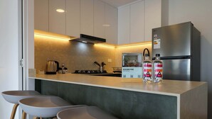 A modern kitchen with a stainless steel refrigerator, a gas stove, and bar stools. - w* | Cityview 2BR w/ Balcony in Miraflores (Miraflores)