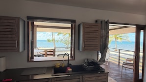 Una cocina moderna con vista a la playa, armarios de madera y un fregadero.