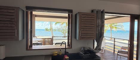 A modern kitchen with a view of the beach, wooden cabinets, and a sink.