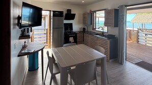 A modern kitchen with a TV, dining table, and chairs. - Le TeRava (Raiatea)