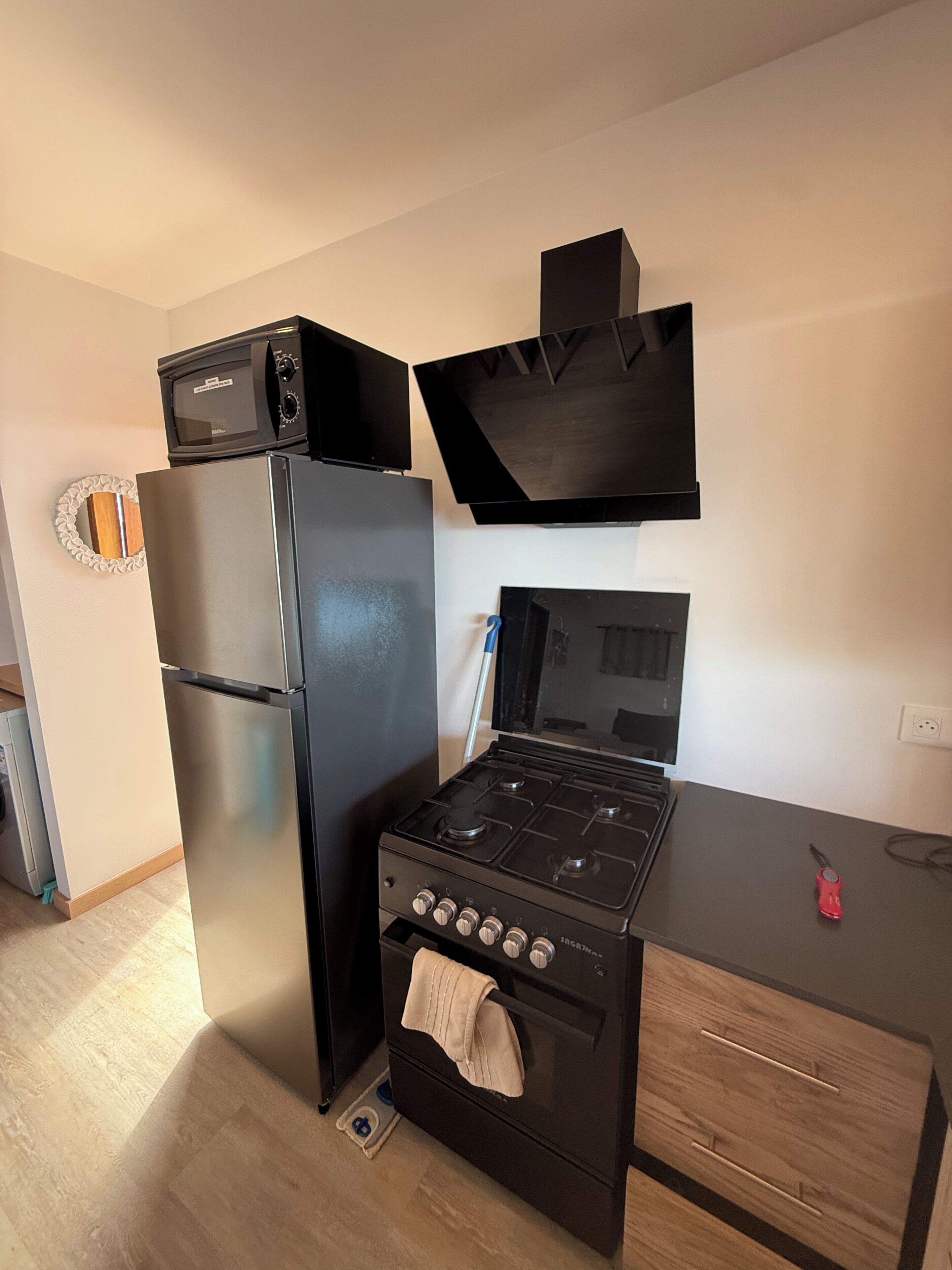 A kitchen with a refrigerator, microwave, stove, and a small oven.