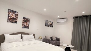 A modern hotel room with a large bed, a sofa, a small table, and artwork on the walls. - Delali Residence Luxury 1BR Near Airport, Pool, Gym & private Terrace (Accra)