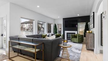 Een moderne woonkamer met een modulaire bank, een glazen salontafel en een open haard.
