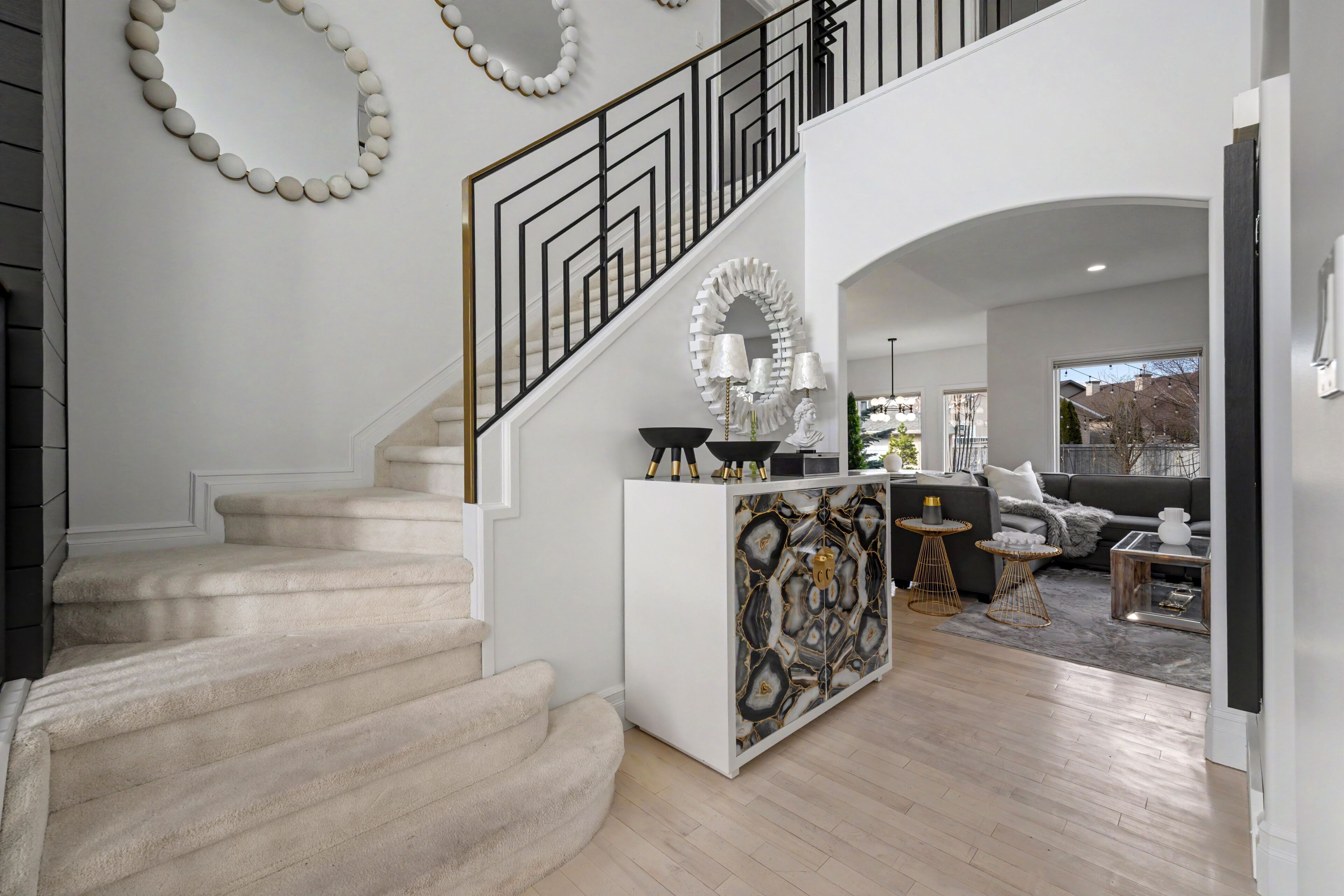 A staircase with a white railing, a white console table with decorative items, and a sofa in a modern living area.
