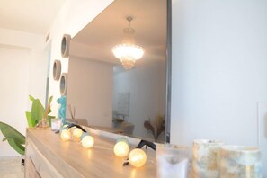 Ein modernes Badezimmer mit einem Holzwaschtisch, runden Spiegeln, einer Chandelierleuchtre und dekorativer Beleuchtung.